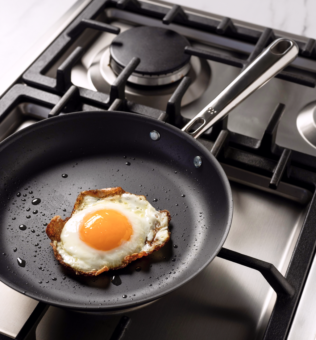 Fried egg cooking in nonstick skillet on gas stove